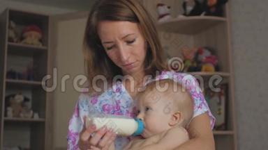 年轻的母亲在家里用<strong>一瓶牛奶</strong>喂她的小儿子。